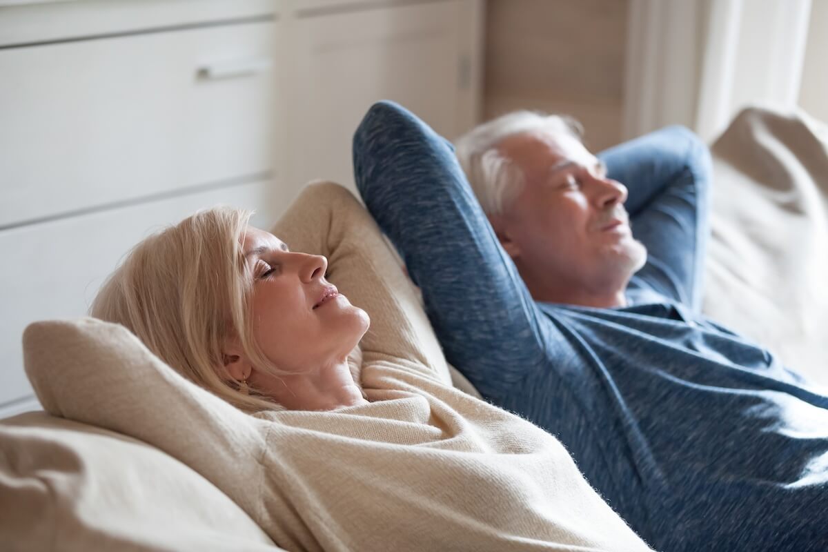 Calm luxury senior living in San Antonio mature couple relaxing on soft comfortable sofa having daytime nap together, carefree middle aged old family breathing fresh air enjoying no stress free peaceful weekend resting on couch